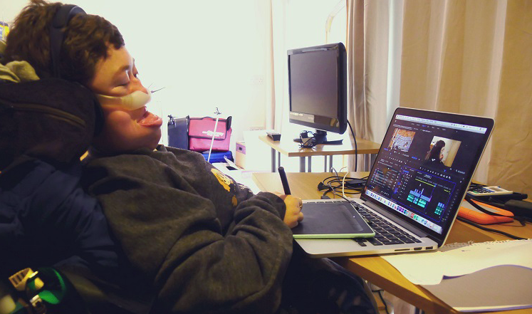 Stephanie-Castelete-Tyrrell-in-her-wheelchair-at-her-laptop-on-a-desk-editing-a-film